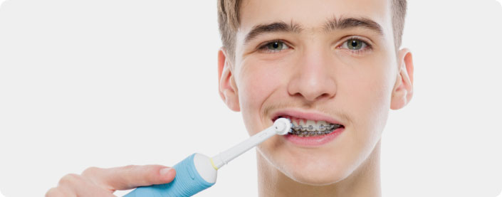 Using electric toothbrush to brush teeth with braces.
