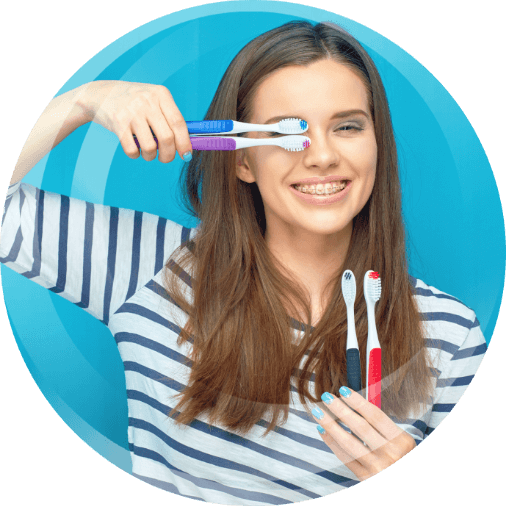 Girl holding manual toothbrushes in multiple colors.