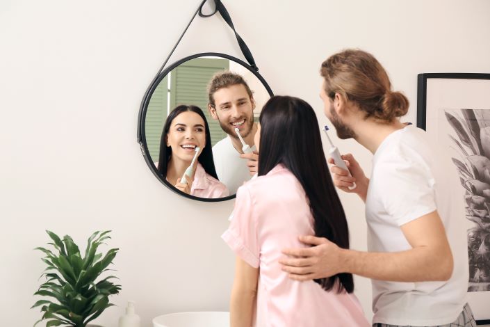 Young couple brushing their teeth together in front of a mirror.