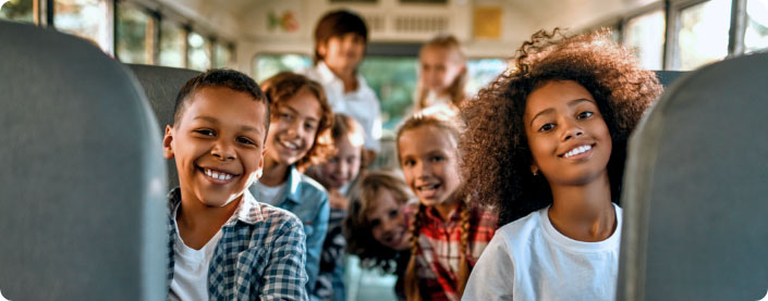 Kids smiling on the bus.