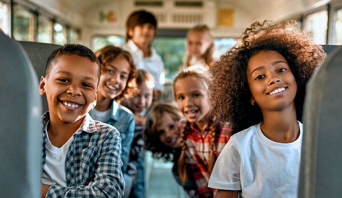 Kids smiling on the bus.