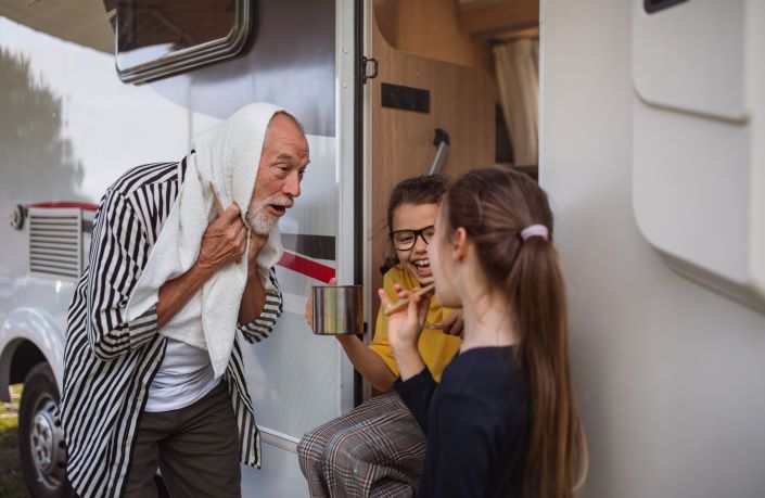 Grandfather and two young girls brush their teeth together while on vacation.